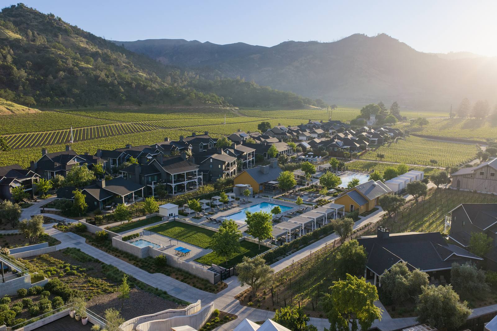 An aerial view of Four Seasons Resort and Residences Napa Valley, its buildings and pools set among vineyards below the Palisades