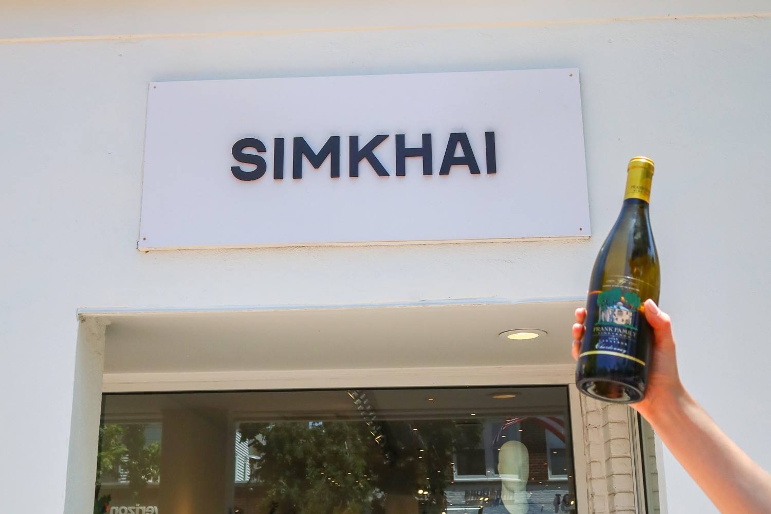 Frank Family wine held before the SIMKHAI sign at New York Fashion Week