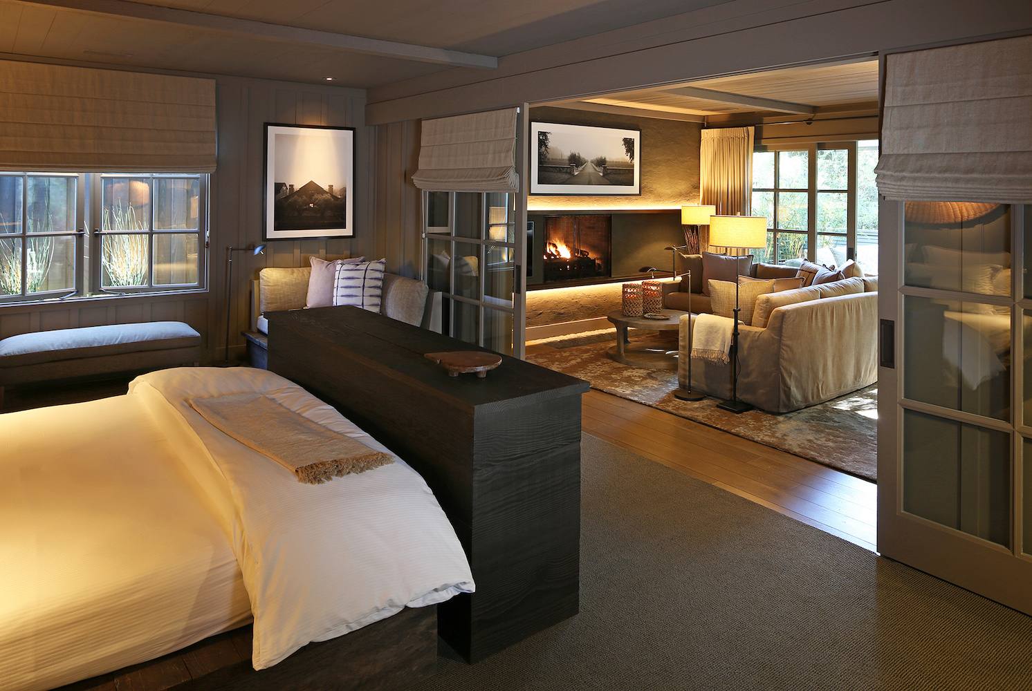 A guest room in the Hill House at Meadowood, with a lit fireplace between the bedroom and sitting room